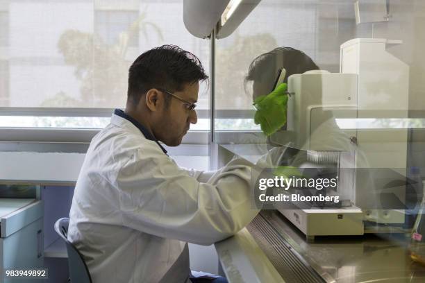 Technician uses an automated pipetting machine to transfer samples of bacteria into a tray of test tubes at a Bugworks Research India Ltd. Laboratory...