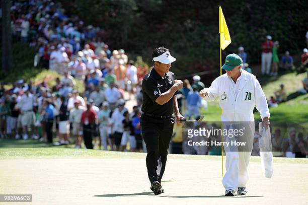 Choi of South Korea celebrates a birdie putt on the eighth green alongside his caddie Andy Prodger during the final round of the 2010 Masters...