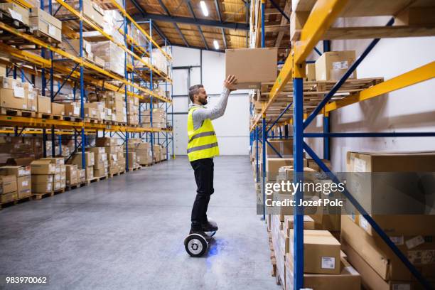 male warehouse worker on hoverboard. - floating shelves stock pictures, royalty-free photos & images