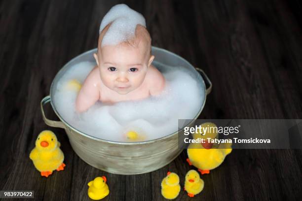 cute baby playing with rubber duck while sitting in metal basin - sitting duck stock pictures, royalty-free photos & images