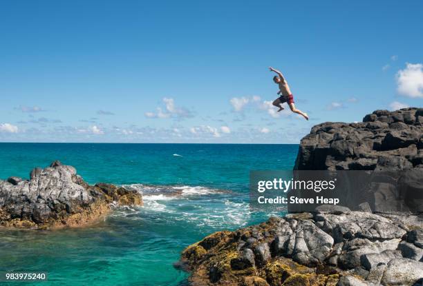 fit young man jumps into ocean at lumahai beach kauai - salto desde acantilado fotografías e imágenes de stock