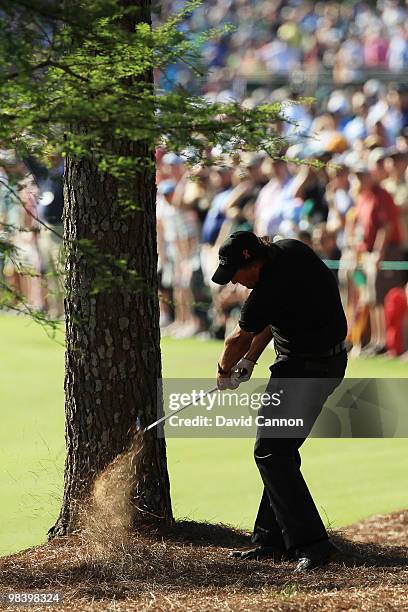 Phil Mickelson plays a shot from the pine needles on the 13th hole during the final round of the 2010 Masters Tournament at Augusta National Golf...