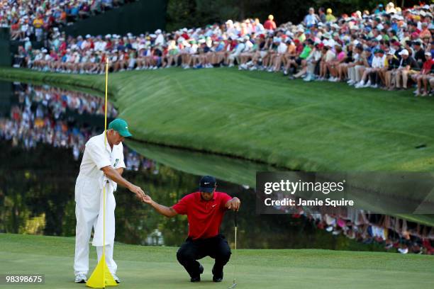 Tiger Woods lines up a putt with the help of caddie Steve Williams in front of a gallery of fans on the 16th green during the final round of the 2010...