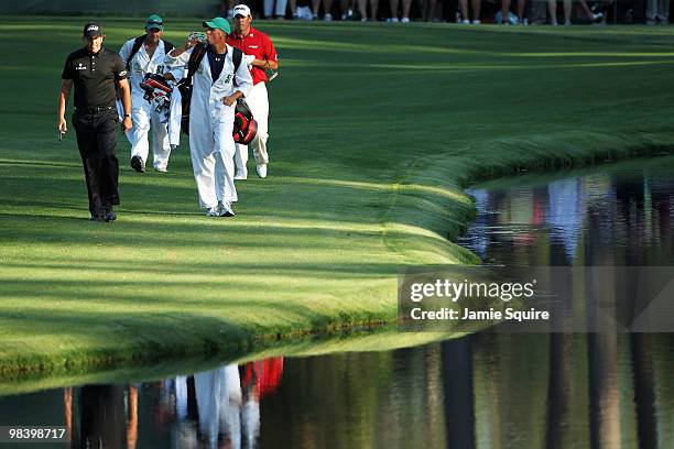 Phil Mickelson and Lee Westwood of England walk to the 16th green with caddies Jim MacKay and Billy Foster during the final round of the 2010 Masters...