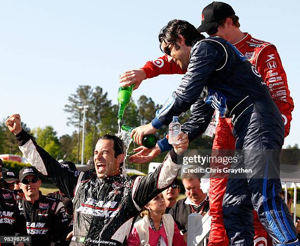 Race winner Helio Castroneves of Brazil, driver of the Team Penske Dallara Honda celebrates has champagne poured on him by Scott Dixon and Dario...