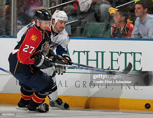 Steven Reinprepcht of the Florida Panthers tries to dig the puck out from the boards against Nate Thompson of the Tampa Bay Lightning at the...