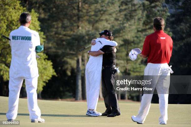 Phil Mickelson celebrates his three-stroke victory with his caddie Jim Mackay as Lee Westwood of England and his caddie Billy Foster look on during...