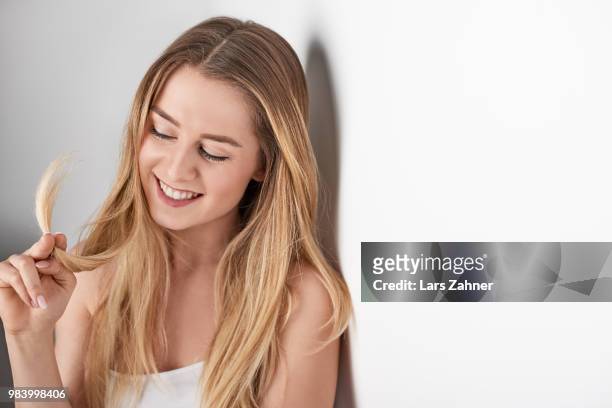 young smiling blonde woman leaning againt wall - againt stock pictures, royalty-free photos & images
