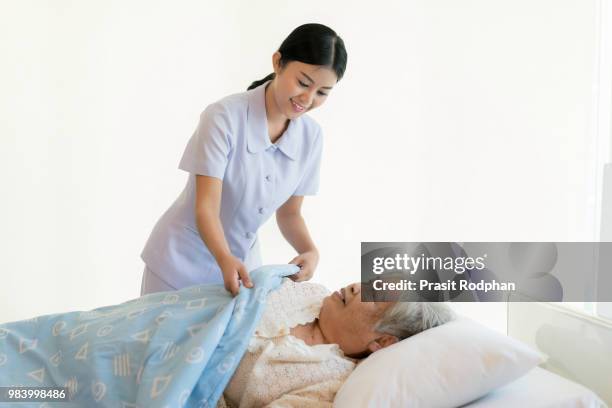 asian nurse in elderly care cover her with a blanket for the eld - eld stock-fotos und bilder