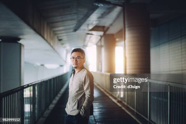 confident young man standing against urban bridge in city - bridge side view stock pictures, royalty-free photos & images