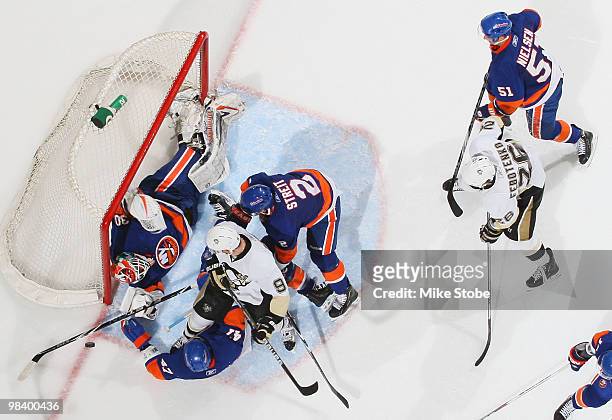 Goaltender Dwayne Roloson of the New York Islanders makes a save against Pascal Dupuis and Ruslan Fedotenko of the Pittsburgh Penguins on April 11,...