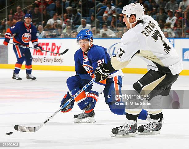 Mark Eaton of the Pittsburgh Penguins controls the puck in front of Kyle Okposo of the New York Islanders on April 11, 2010 at Nassau Coliseum in...