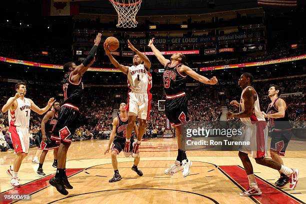 Jarrett Jack of the Toronto Raptors drives hard to the basket and splits defenders Hakim Warrick and Joakim Noah of the Chicago Bulls during a game...