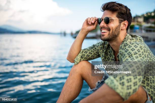 bonito homem sorridente, olhando para longe. - água parada - fotografias e filmes do acervo