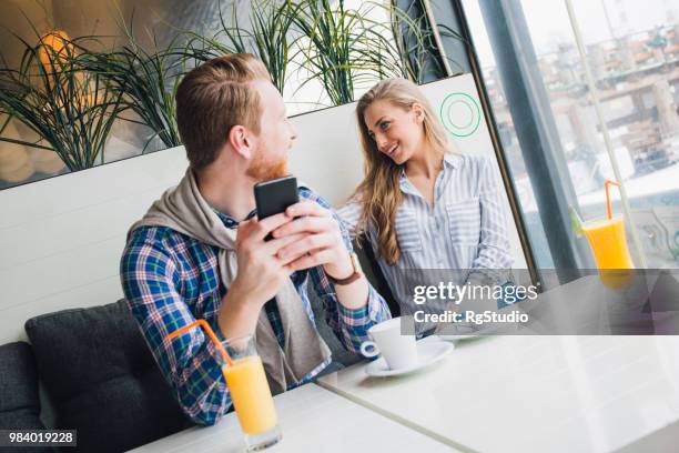 gelukkige paar met mobiele telefoon drinken koffie en oranje sap bij koffie shop - happy mobile stockfoto's en -beelden