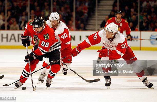 Patrick Kane of the Chicago Blackhawks skates past Valtteri Filppula and Henrik Zetterberg of the Detroit Red Wings at the United Center on April 11,...