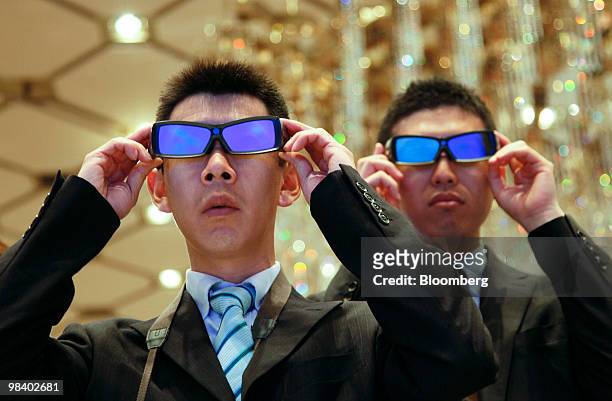 Visitors wearing 3-D glasses watch 3-D images on Sharp Corp.'s four-primary-color 3-D liquid-crystal display panels at a media preview in Tokyo,...