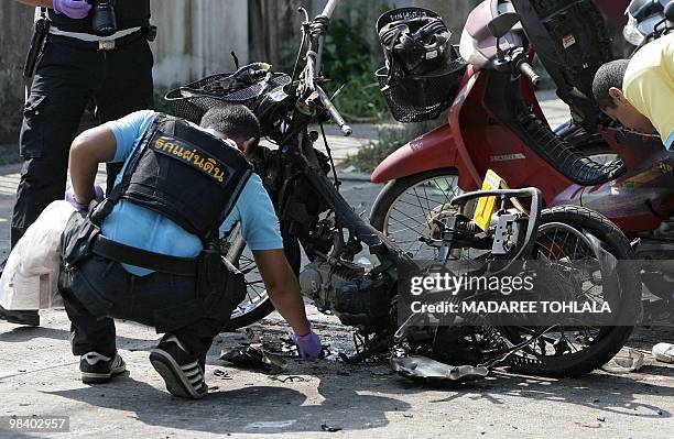 Member of a Thai bomb squad inspects the scene where a motocycle was destroyed in a blast in front of the district officers office, suspected of...