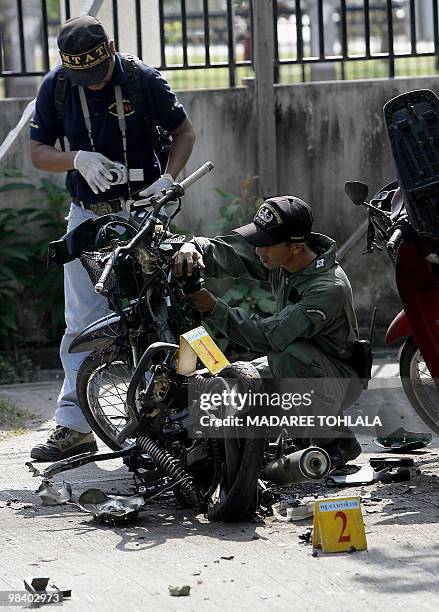 Members of a Thai bomb squad inspect the scene where a motocycle was destroyed in a blast in front of the district officers office, suspected of...