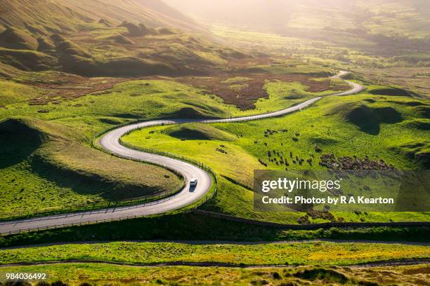 car driving in the hills of england on a sunny evening - strada tortuosa foto e immagini stock