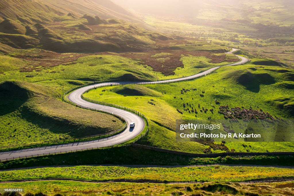 Car driving in the hills of England on a sunny evening