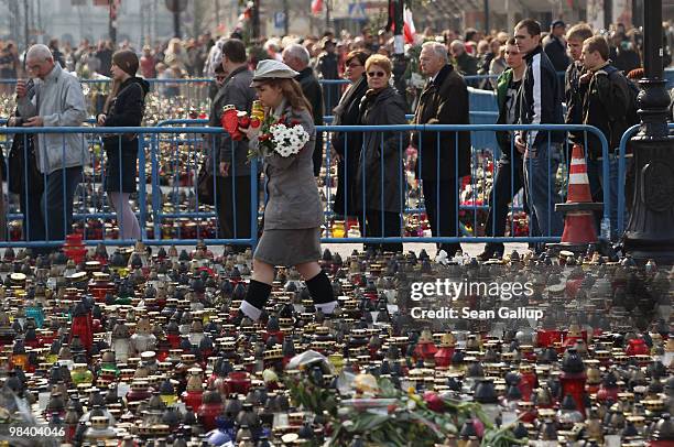 Girl scout helps to arrange flowers given to her by mourners as others wait in line to sign books of condolence outside the Presidential Palace in...