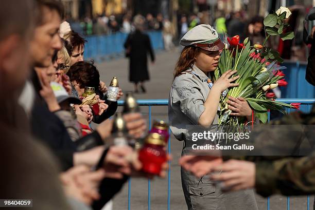 Polish girl scout accepts flowers and a soldier accepts candles from mourners to lay them outside the Presidential Palace in memory of late Polish...