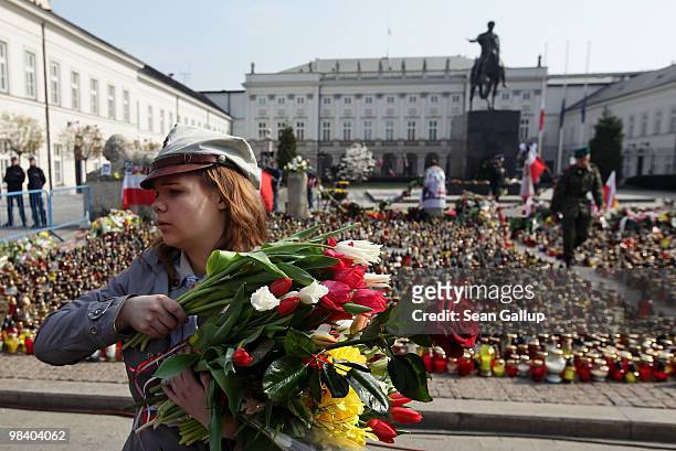 Polish girl scout accepts flowers from mourners to lay them outside the Presidential Palace in memory of late Polish President Lech Kaczynski on...