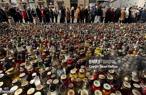 People wait in line to sign books of condolence next to a sea of candles left by mourners outside the Presidential Palace in memory of late Polish...