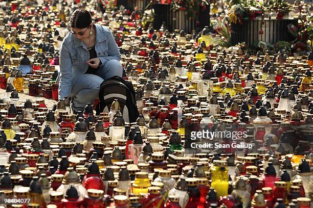 Young woman lights a candle among hundreds of others left by mourners outside the Presidential Palace in memory of late Polish President Lech...