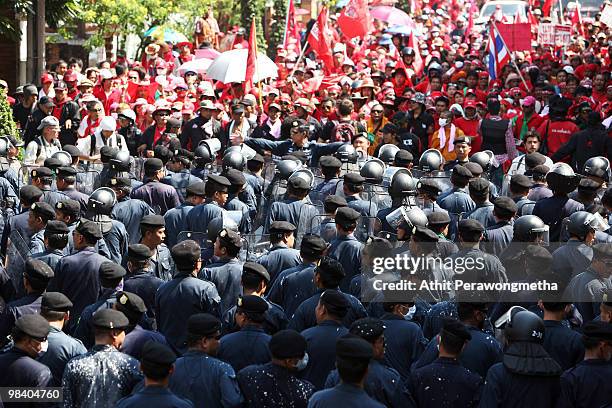 Thai riot policemen confront Red Shirt supporters of former Prime Minister Thaksin Shinawatra during a funeral procession for the victims of clashes...