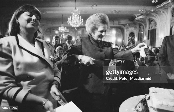 British Prime Minister Margaret Thatcher cuts the cake with a ceremonial sword during a 300 Group lunch at the Savoy Hotel in London, 18th July 1990.