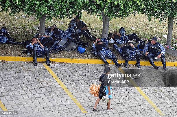 Street vendor walks past policemen resting at the parking lot of the hotel where the talks are taking place on October 19, 2009 in Tegucigalpa. A...