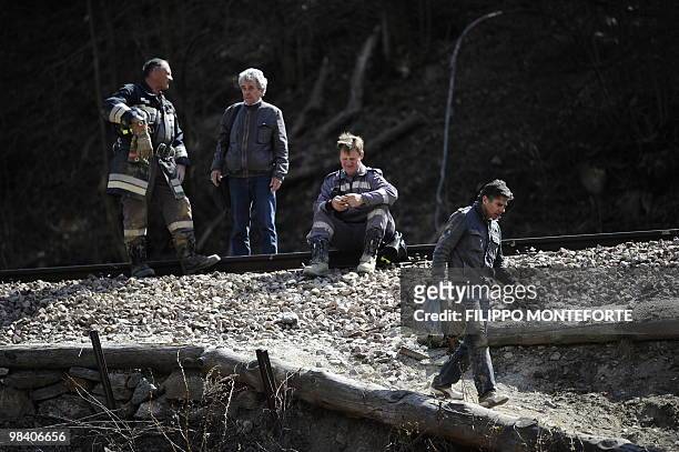 Rescuers stand near the railtracks hours after a passenger train was thrown from its tracks by a landslide in mountains near Laces and Castebello,...