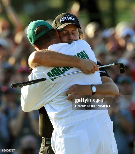 Phil Mickelson of the US hugs his caddie Jim 'Bones' Mackay after sinking his putt on the 18 hole to win the 2010 Masters Tournament at Augusta...