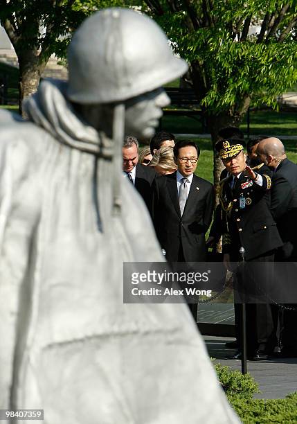 Korean President Lee Myung-bak listens to an aide during his visit to the Korean War Memorial for a wreath laying to commemorate the 60th anniversary...