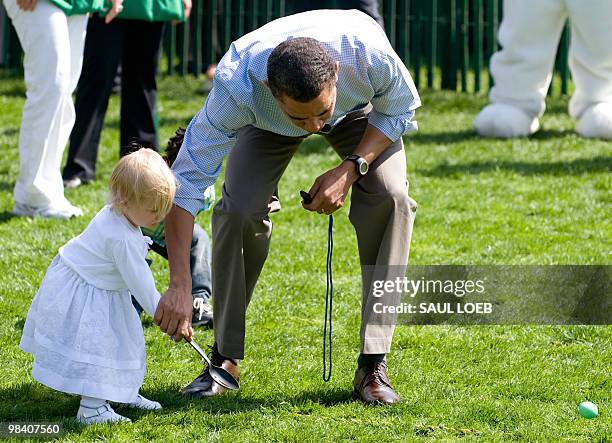 President Barack Obama helps 18-month-year-old Lilian Plouffe, daughter of former Obama campaign manager David Plouffe, with her egg during the start...