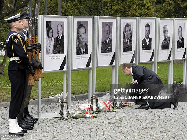 Polish defence minister Bogdan Klich lays flowers, on April 12 at the ministry in Warsaw, in front of pictures of victims' of the plane crash that...