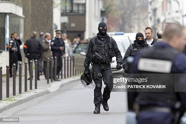 Two French special police force members walk in the security perimeter around La Santé prison in Paris set following an hostage situation on April...