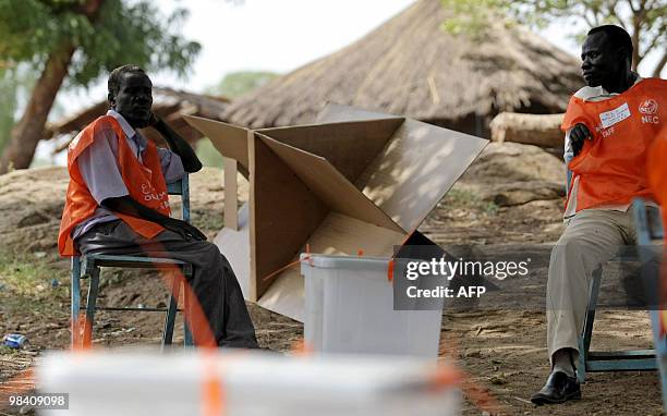 Sudanese electoral officials wait next to empty ballot boxes for the arrival of new voting material after what they had received earlier turned out...