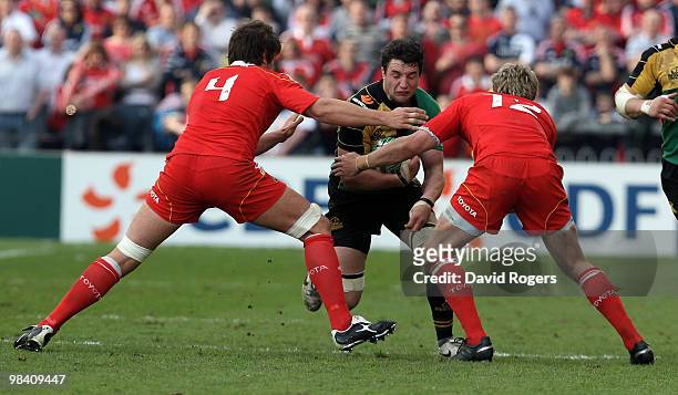Phil Dowson of Northampton is tackled by Donncha O'Callaghan and Jean de Villliers during the Heineken Cup quarter final match between Munster and...