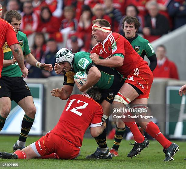 Juandre Kruger of Northampton is tackled by Jean de Villiers and Mick O'Driscoll during the Heineken Cup quarter final match between Munster and...
