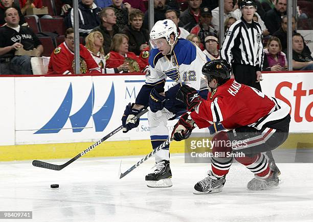 David Backes of the St. Louis Blues takes the puck up the ice as Niklas Hjalmarsson of the Chicago Blackhawks reaches in from the side on April 07,...