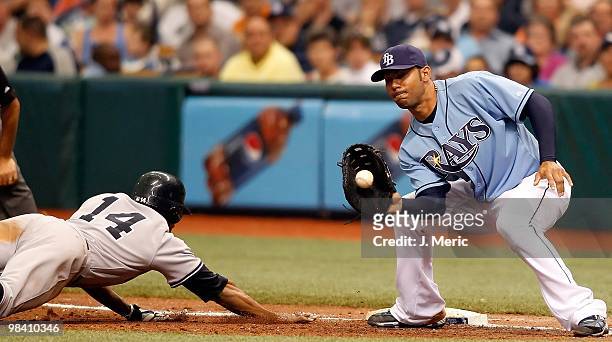 First baseman Carlos Pena of the Tampa Bay Rays takes the throw at first as outfielder Curtis Granderson of the New York Yankees gets back safely...