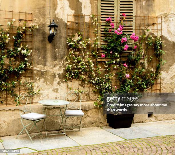 a street scene with iron chairs and table, old wall an potted plants. alba, italy. - italian cafe culture stock pictures, royalty-free photos & images