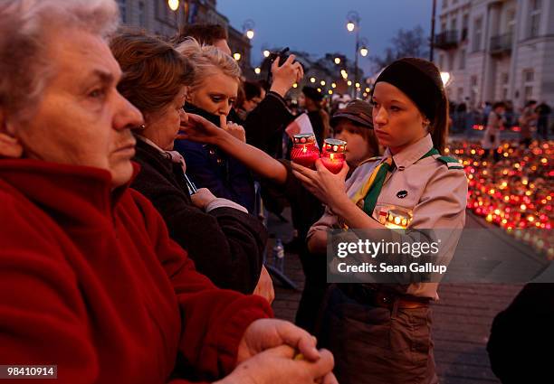 Polish girl scout accepts candles from mourners to lay them outside the Presidential Palace in memory of late Polish President Lech Kaczynski on...