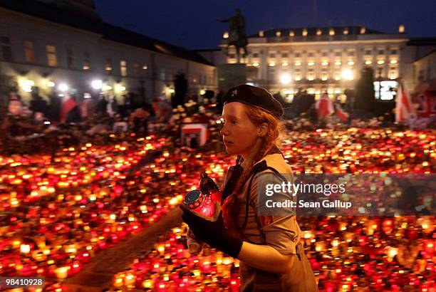 Polish girl scout accepts candles from mourners to lay them outside the Presidential Palace in memory of late Polish President Lech Kaczynski on...