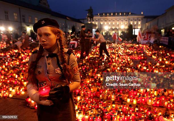 Polish girl scout carries a candle she accepted from mourners to lay it outside the Presidential Palace in memory of late Polish President Lech...
