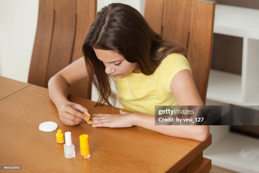 Girl, 12-13 years, painting her finger nails with nail polish