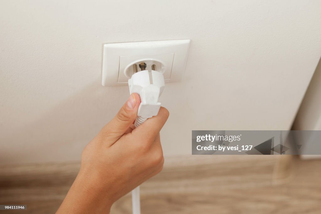 Hand plugging in or out an electric cord into a socket